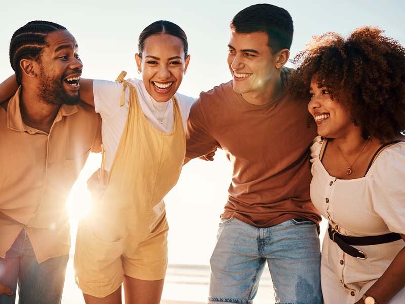 Four friends smiling together at the beach