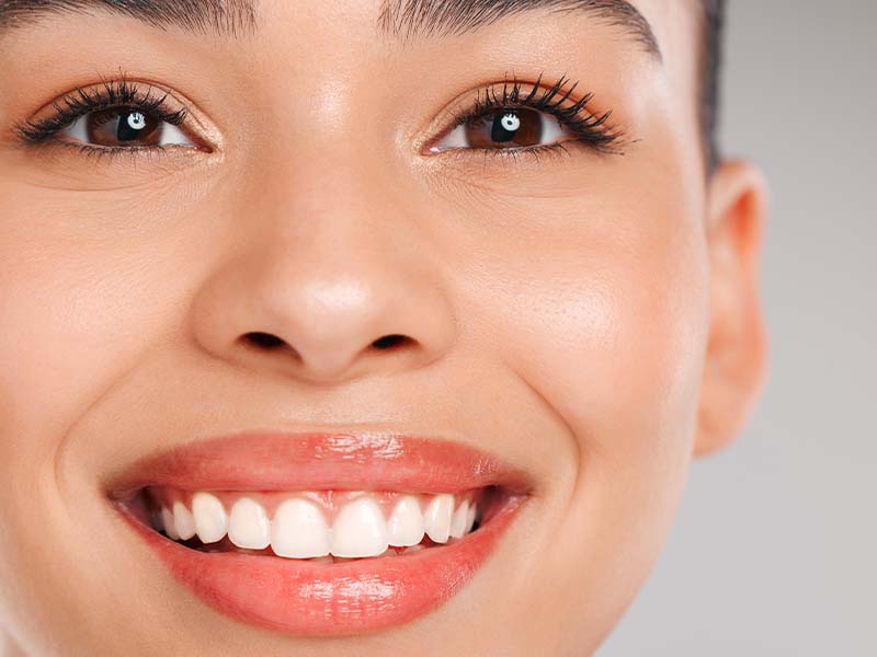 Close-up studio portrait of a woman with a bright smile