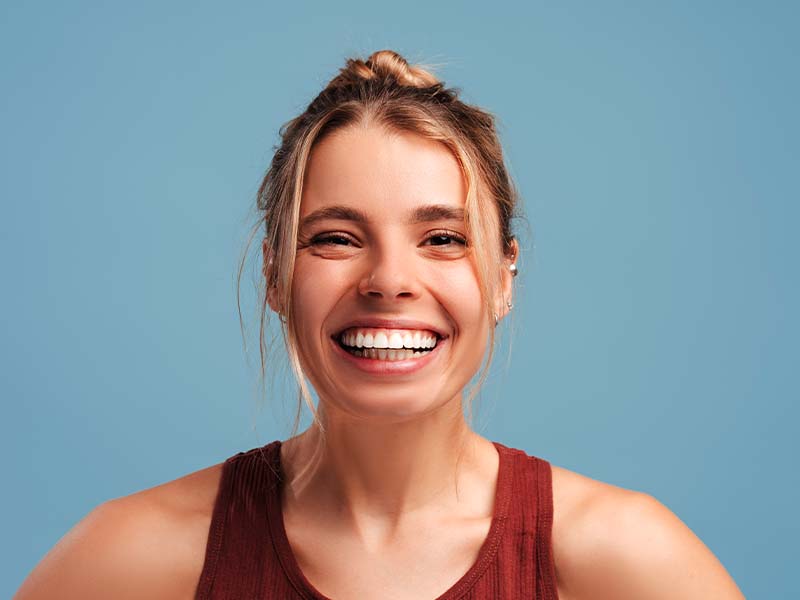 Athletic young woman smiling against a blue background
